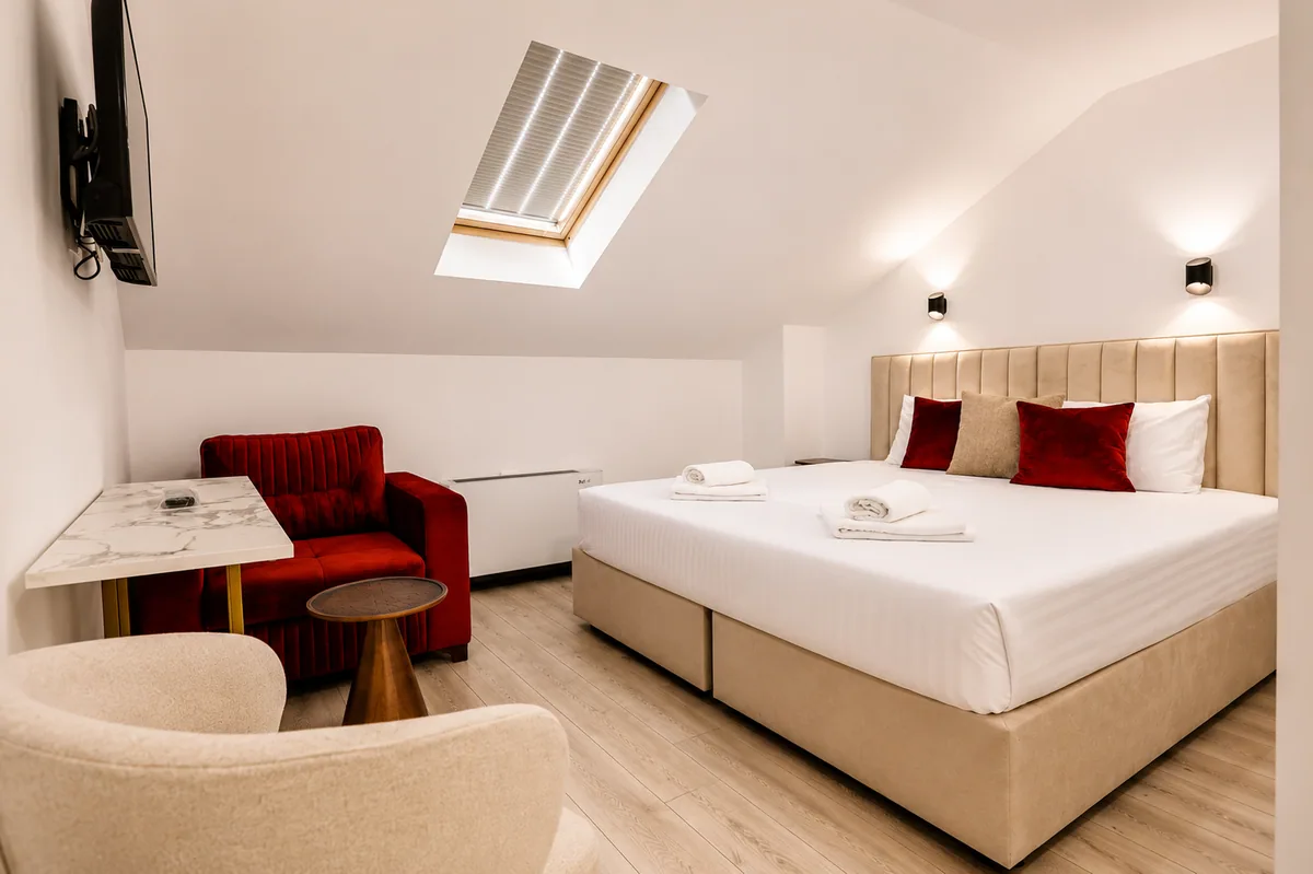 Dachzimmer mit Doppelbett und rotem Sessel