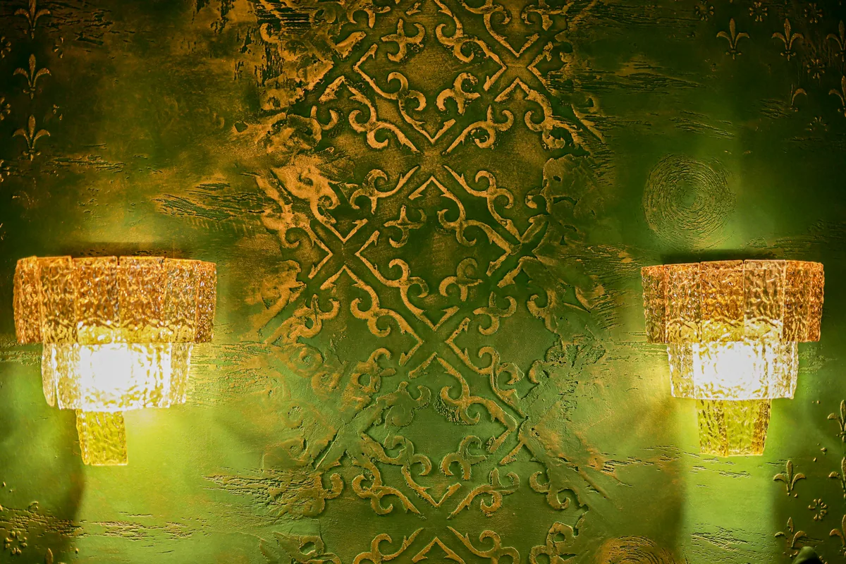 Kristallwandleuchten vor einer grün-goldenen Wand